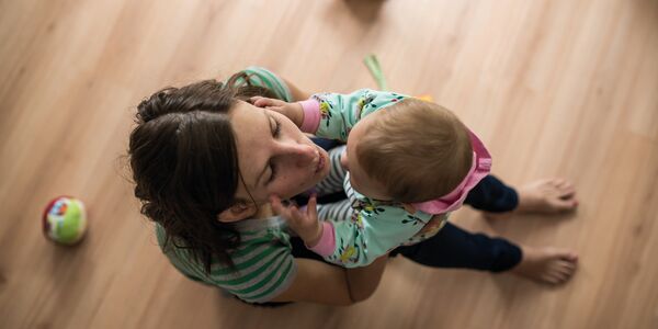 Mutter sitzt mit Baby am Boden