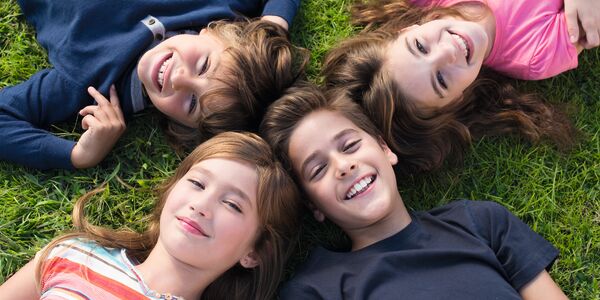 Vier Kinder liegen in der Wiese