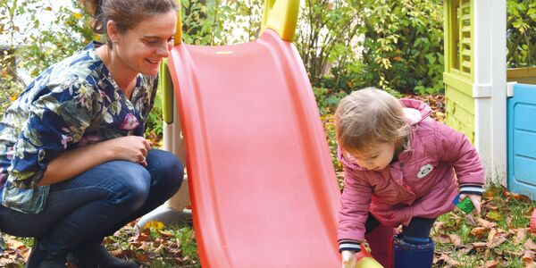Mutter und Kleinkind an der Rutsche im Herbst