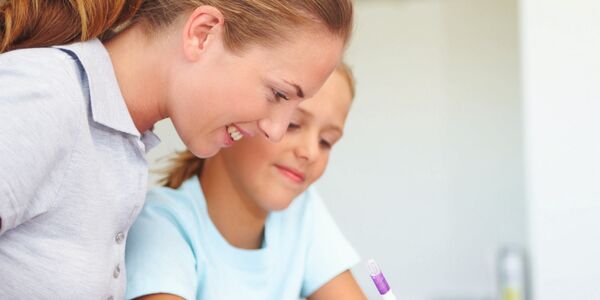 Lehrerin schaut Schülerin über die Schulter
