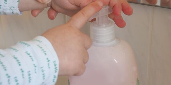 Mutter hilft Kinderhand am Seifenspender