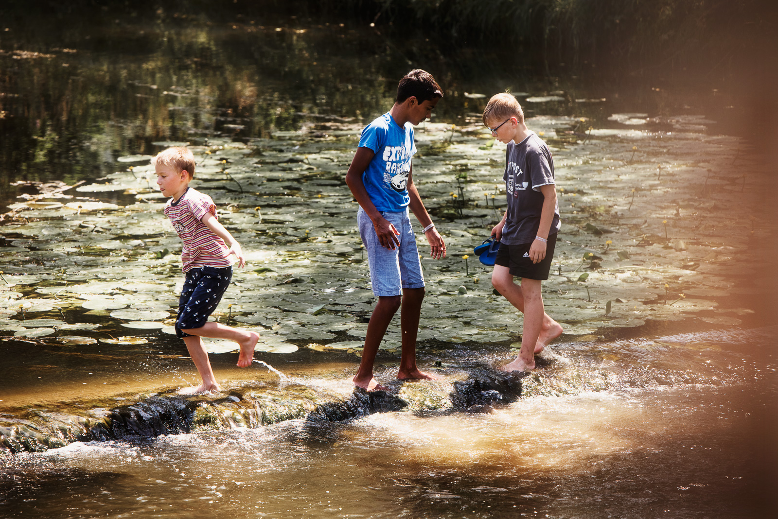 Drei Kinder spielen am Bach