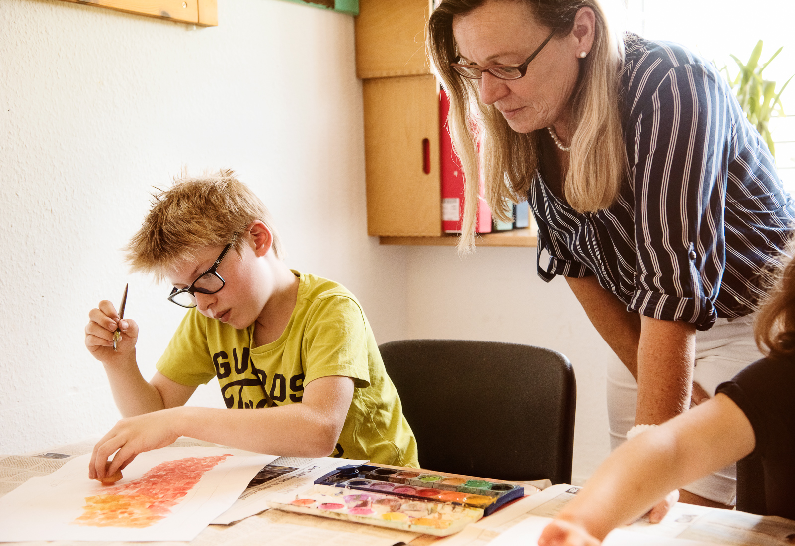 Junge und Lehrerin beim Malunterricht